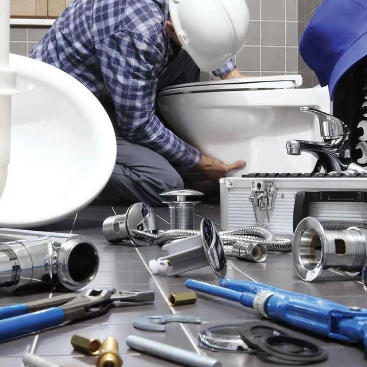 Professional plumber installing a toilet with tools and pipes on the bathroom floor